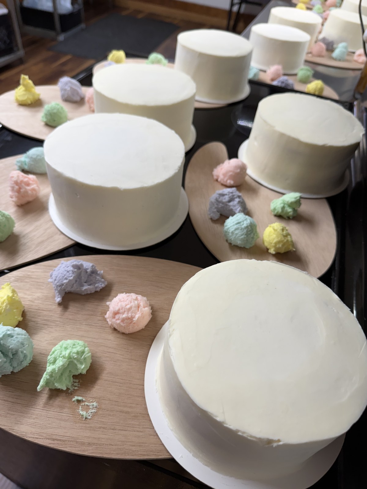 Frosted cakes set out with pastel icing on wooden palettes for a decorating party